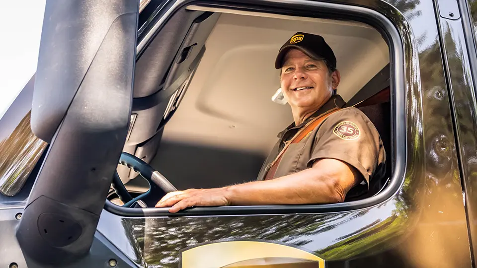 Smiling UPS driver in a truck.